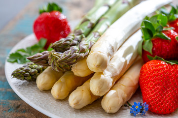 Spring in Netherlands, high quality Dutch white asparagus, washed and peeled on board with fresh red ripe strawberry