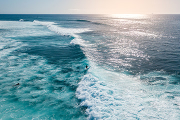 aerial view of a surfer riding a surf at sunset
