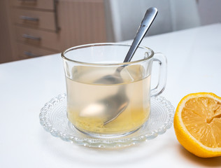 Glass cup of hot ginger tea with ginger rhizome (root) sliced and lemon, isolated on white background.