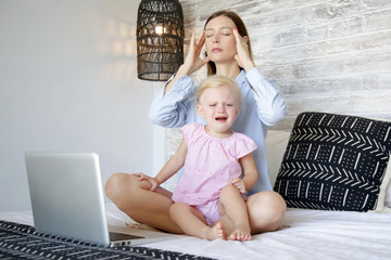 Work from home with a little one. Young mother trying to work on laptop while babysitting. Stressful mum trying to multitask. 