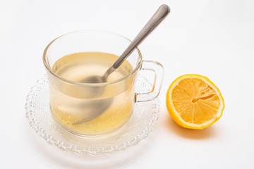 Glass cup of hot ginger tea with ginger rhizome (root) sliced and lemon, isolated on white background.