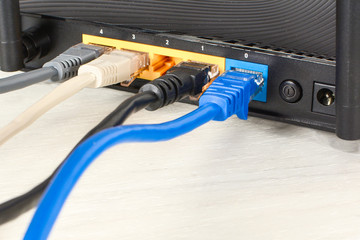 Home wi-fi router for internet connection with four patch cords with rj45. Concept home network, close-up on white wooden table.
