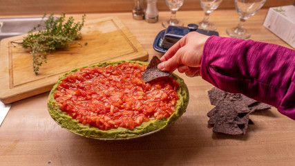 Casual girl dipping into Mexican salsa dip while holding nacho tortillia chips