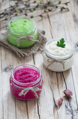Fototapeta na wymiar Russian appetizer horseradish with beetroot, green horseradish wasabi, white horseradish with lemon in jars on a wooden background in rustic style