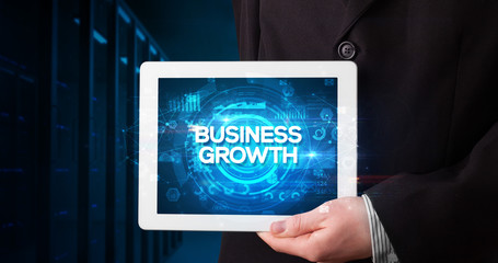 Young business person working on tablet and shows the inscription: BUSINESS GROWTH, business concept