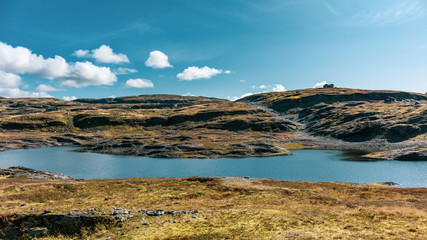 Norway high mountains lake on sunny day landscape. Wild nature travel, blue sky, bright color graded colors. Hiking scandinavian scenery