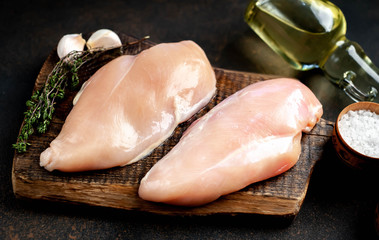 raw chicken breast on a cutting board with spices and a meat knife on a stone background © александр таланцев
