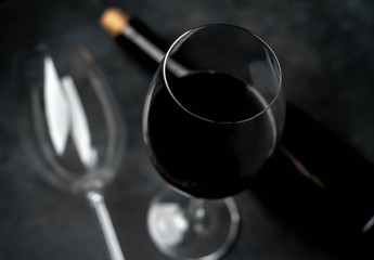 Bottle of red wine and glasses 
with wine  on a stone background. Top view with copy space.