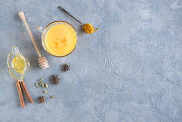 Cup of ayurvedic golden turmeric latte milk with curcuma powder and anise star on gray. Top view. Prevention of coronavirus.