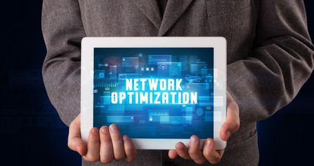 Young business person working on tablet and shows the digital sign: NETWORK OPTIMIZATION