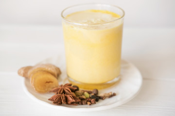 Traditional Indian drink. turmeric milk or golden milk with cloves, pepper, cinnamon and turmeric. close up view of ginger yellow latte. healthy drink to support tonus. immunity boost tea. 