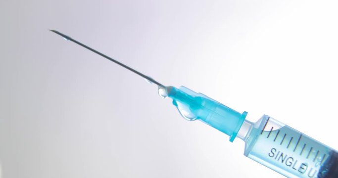 Syringe with needle and blue vaccine against coronavirus, sars, flu on light background during pandemic, closeup view. Vaccination concept, COVID-19. Epidemic of seasonal virus. Disposable syringe.