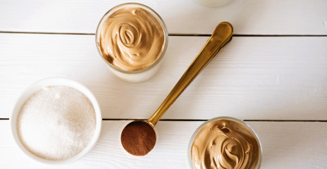 Iced frothy Dalgona Coffee, a trendy fluffy creamy whipped coffee. Korean drink latte espresso with coffee foam. cups and spoon with instant coffee and sugar. top view