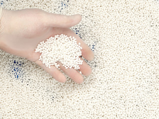 The lab assistant takes with his hand of white plastic polymer granules.