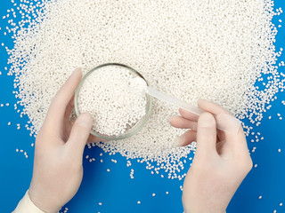 laboratory assistant taking new batch of white plastic polymer granules.
