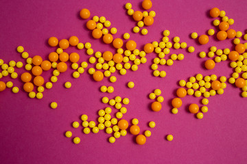 bunch of colorful pills for viral diseases. Prevention of influenza, coronavirus, covid-19. handful of yellow, orange vitamins on purple background. medical healthcare concept. flatlay, top view