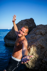 Happy man guy joy on vacation, stands on the shore and looks at the sea. Men's shorts, sun, beach
