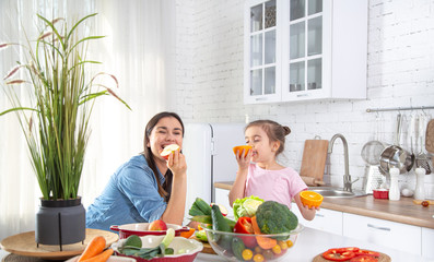 Mom and daughter in the kitchen with fruits and vegetables.
