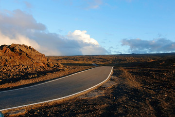 Hawaii Big Island nature background. Mauna Loa landscape with paved road to the summit through lava fields during sunset.