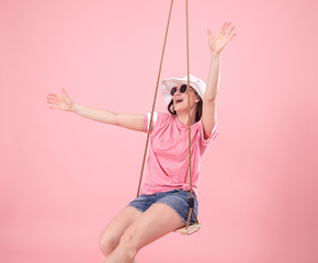 Young woman on a swing on a pink background.