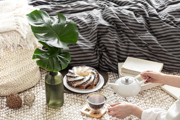 Hands of a young woman pour tea from a teapot.