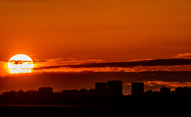 Big sun at sunset over the city