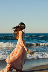Fototapeta na wymiar young and beautiful bride. Alone bride walking on the beach in simple wedding dress. Bride crown.