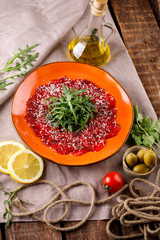 carpaccio with arugula and mushrooms on an orange plate in the restaurant, next to the products for...