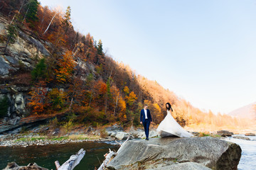 bride and groom on picturesque landscape, sky and forest. autumn