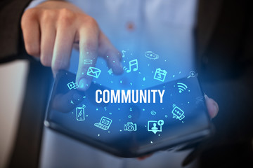 Businessman holding a foldable smartphone with COMMUNITY inscription, social media concept