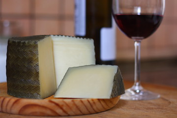 queso manchego, hecho en españa acompañado de una copa de vino tinto.