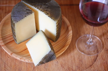 queso manchego, hecho en españa acompañado de una copa de vino tinto.