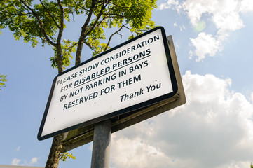 Sign asking drivers to show consideration for disabled persons by not parking in bays reserved for them