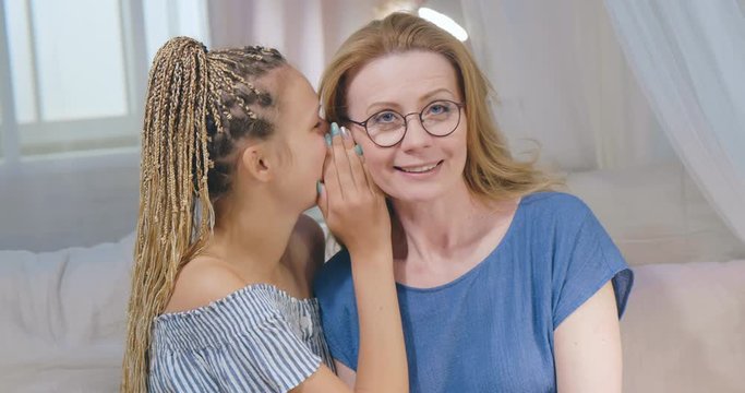 Adult happy daughter whispering a secret or positive news to mother's ear. Respectful relationships between different family generations