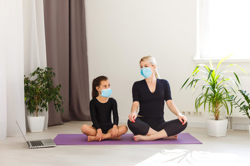 COVID-19 Shutdown. Mother and daughter in quarantine doing yoga indoors. Mother and daughter doing...