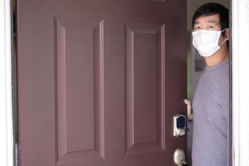 man stay home wear mask at the front door for self quarantine to stop the corona virus, covid19 pandemic outbreak . keep social distancing by call friend and doctor.