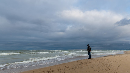 Samotny człowiek na plaży nad Bałtykiem podczas sztormu