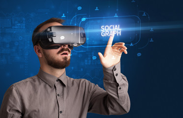 Businessman looking through Virtual Reality glasses with SOCIAL GRAPH inscription, social networking concept