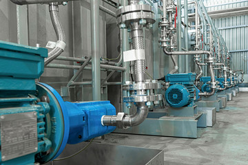 Industrial equipment. New blue electric motors with pumps on the stainless steel production line. Industrial background. Additive pump station in petrochemical technology.