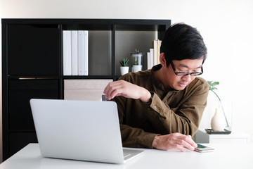 40s asian man with eye glasses working on laptop or computer notebook in modern working space at home office and online learning for corona virus or covid 19 pandemic.