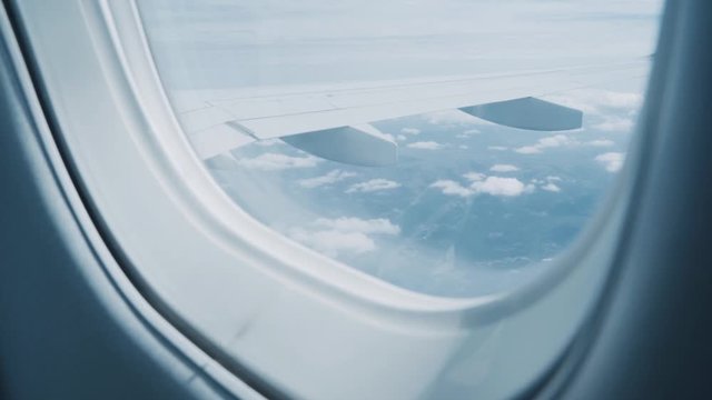 Side view from a plane window of the aircraft wing and clouds. Travel and holidays concept. Delay flight and commute traveler lifestyle. Airplane trip to new destination.