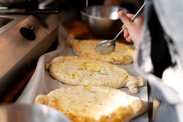 Culinary master class. Closeup of people hands preparing khachapuri. Traditional georgian cheese bread. Georgian food