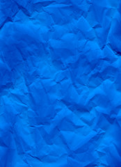 Blue crumpled paper texture background. A close-up abstract macro photo of creased paper. Abstract flatlay, top view. Vertical format. Free space for your text. Ultramarine colored
