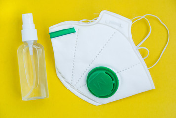 Respirator ffp and antiseptic lying on a yellow background flat lay