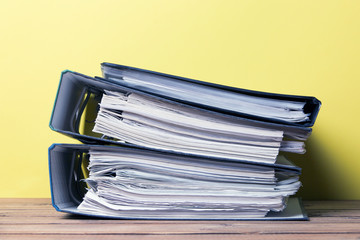 A stack of folders with documents on a wooden table
