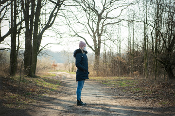 Sick woman with a hat alone on a walk in the forest, wearing protective mask against transmissible...
