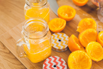 Fresh natural orange juices and slices of squeezed oranges on a wooden table.