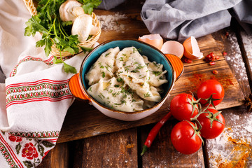 Russian dumplings with butter and herbs on the background of the national tablecloth
