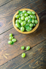 Sweet fresh gooseberry berry in a bowl on wood background.
