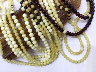 Many Baltic amber round beads lie on a large piece of natural amber. Template for decorating a...